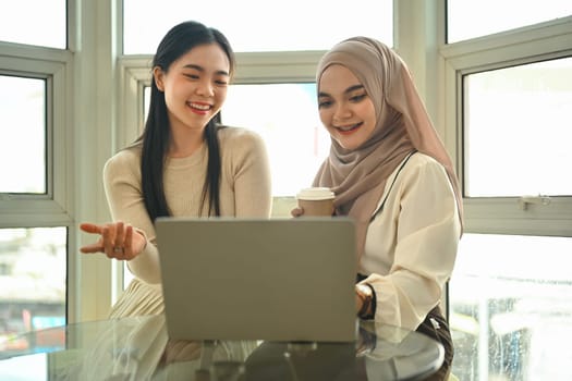 Shot of two female friends doing online shopping or browsing internet on laptop together.