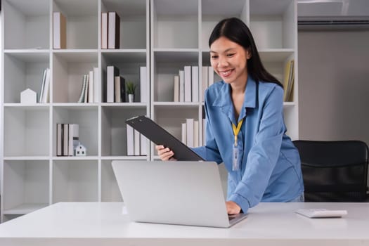 Businesswoman uses laptop and calculator to do finance, paperwork. Mathematics clipboard on table in office and business background, tax, accounting, statistics and analytical research concept..