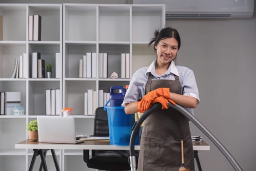 Portrait of a beautiful young housewife smiling and happy, holding cleaning supplies in the office. cleaning supplies, housekeeper.