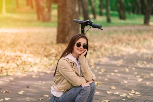 Young woman riding an electric scooter in autumn park. Green transport, traffic jam problems.