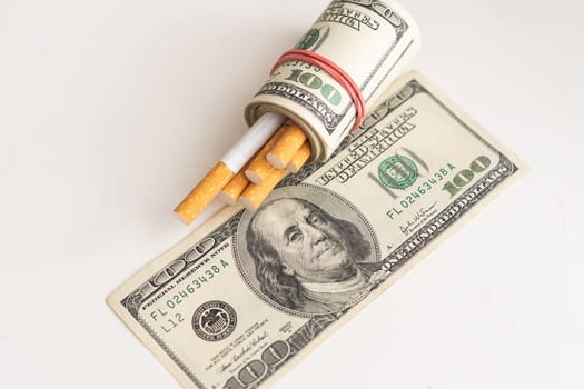 A roll of 100-dollar bills with cigarettes on a background. Concept of expensive cigarettes. High quality photo