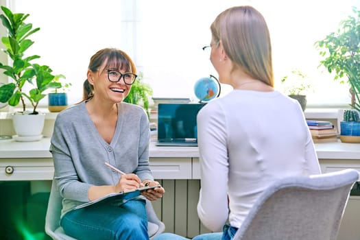 Female psychologist therapist working with young teen girl sitting in office. Teenage female student at therapy meeting with counselor. Psychology therapy psychotherapy youth mental health treatment