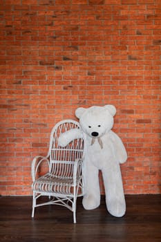 Big polar bear toy and chair against brick wall