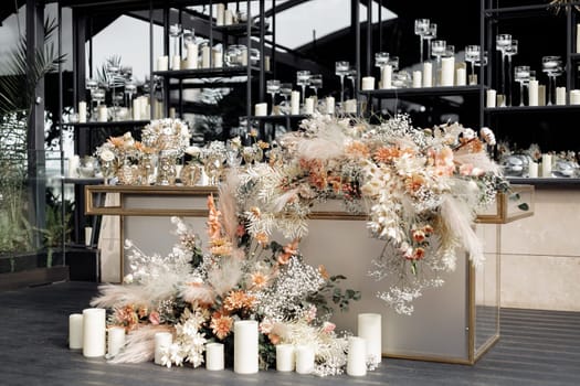 Decorated glass table against mirrored wall with floating candles in glass vases. Modern luxury wedding decor in expensive tones with flowers and gold.