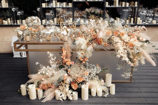 Decorated glass table against mirrored wall with floating candles in glass vases. Modern luxury wedding decor in expensive tones with flowers and gold.