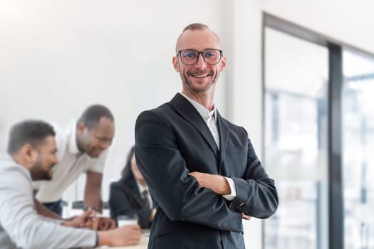Portrait attractive young businessman A successful business executive stands with his arms crossed in his office with a happy smile on his face