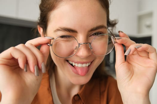 Close up portrait of beautiful, charismatic young woman in glasses, showing tongue and smiling, wearing spectacles.