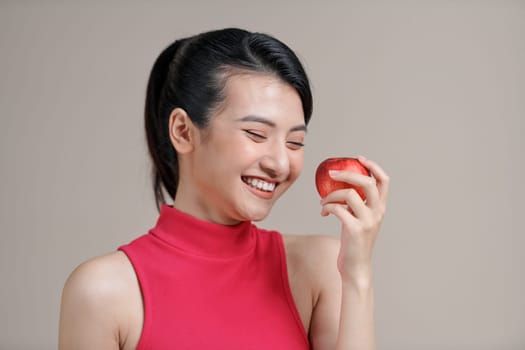 Woman with perfect smile holding apple on beige background
