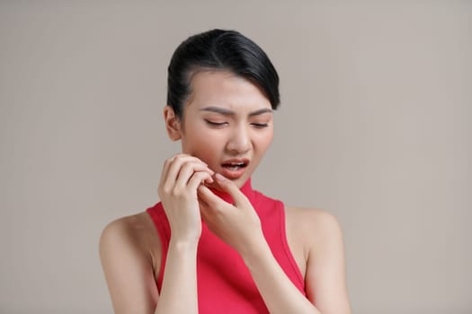 Asian woman pressing her cheek with a painful expression as if she is having a terrible toothache
