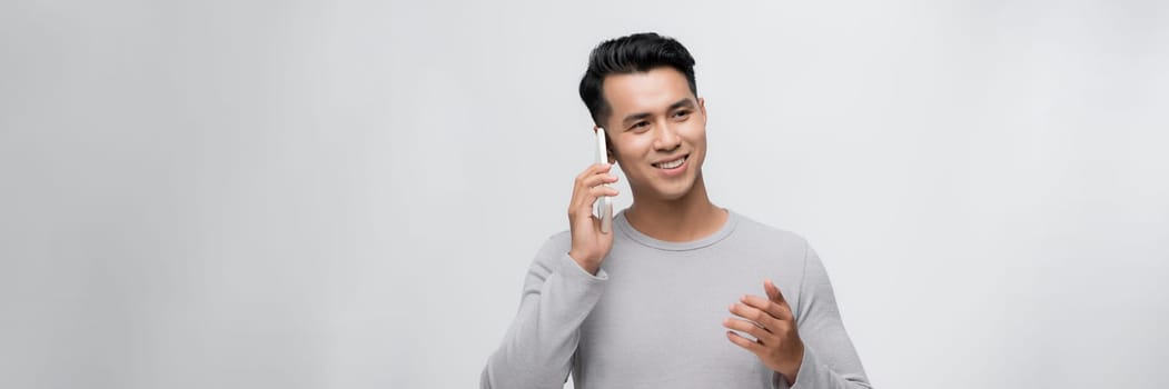 Young man isolated on white background keeping a conversation with the mobile phone with someone