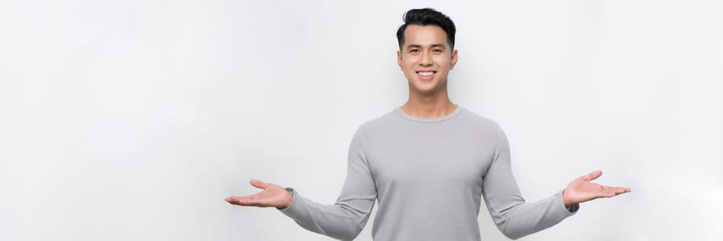 Attractive young Asian man smiling and welcoming heartily with arms open on banner