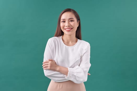 Young asian woman isolated on green background who feels confident, crossing arms with determination.