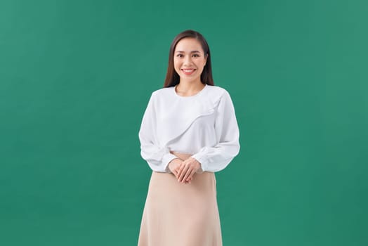Portrait of a happy woman standing with arms folded isolated on a green background