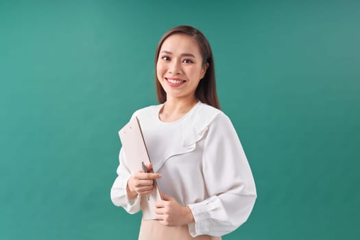 Attractive young asian woman hold clipboard with papers document writing on green background