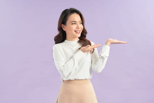 Beautiful young Asian woman show palm hand on color background