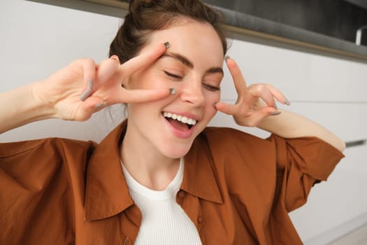 Carefree woman singing along song, listens to music in wireless headphones, enjoying sound quality, dancing with hands.