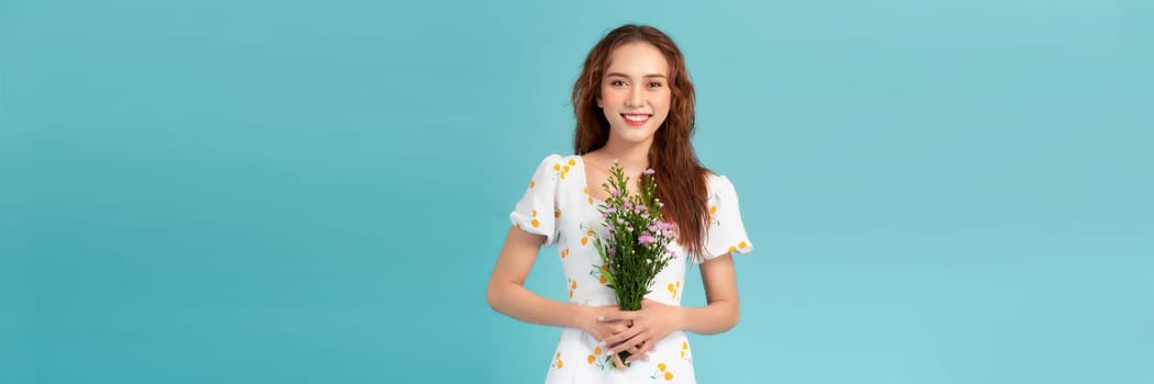 Young beautiful girl with long hair and hat posing with a bouquet of wildflowers. 