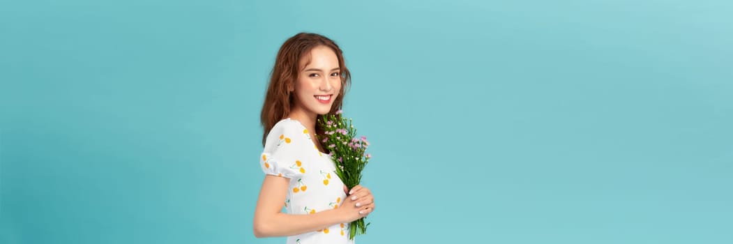 Young beautiful girl with long hair and hat posing with a bouquet of wildflowers. 