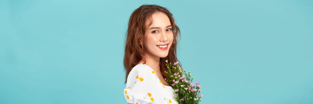 A beautiful young woman in summer dress holding wildflowers bouquet