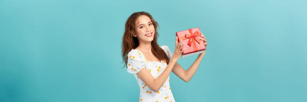 Banner of a happy young girl holding present box and looking at copy space isolated