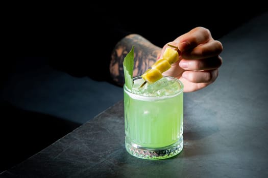 green cocktail with lime in a glass glass with ice and pieces of fruit