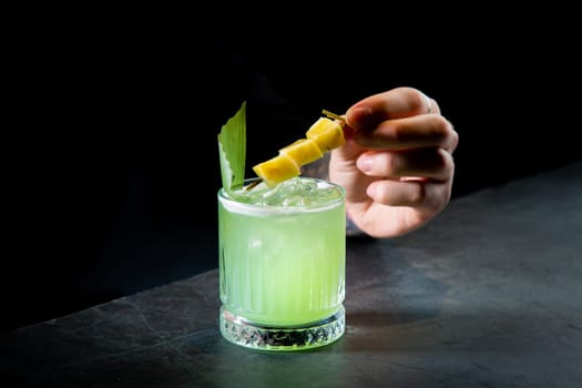 green cocktail with lime in a glass glass with ice and pieces of fruit