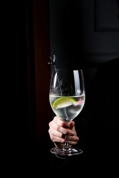 transparent cocktail with ice on a dark background in hand