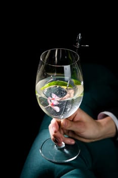 transparent cocktail with ice on a dark background in hand