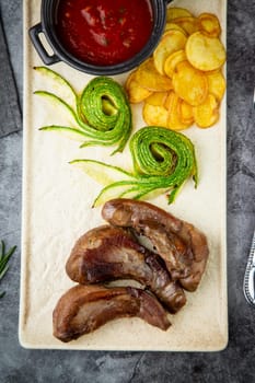 meat ribs with avocado, chips and ketchup on a white plate