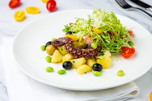 salad with olives, herbs, cherry tomatoes, potatoes and octopus tentacles