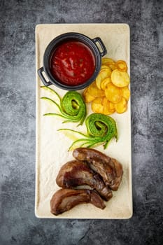 meat ribs with avocado, chips and ketchup on a white plate