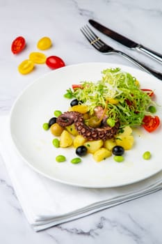 salad with olives, herbs, cherry tomatoes, potatoes and octopus tentacles