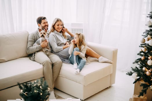 Happy family: mom, dad and daughter. Family in a bright New Year's interior with a Christmas tree