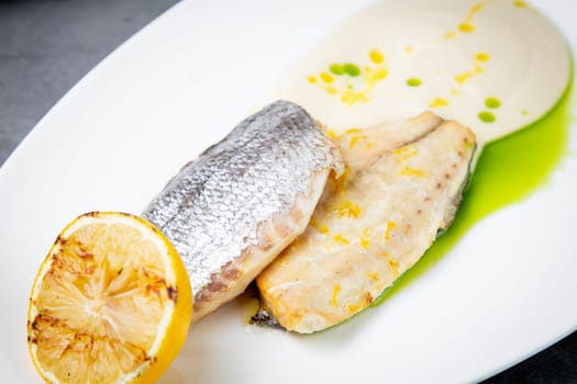 pieces of fried fish with sauce and fried lemon on a white plate