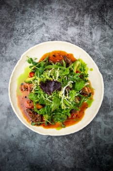 meat gravy with meat, cherry tomatoes and a bunch of greens on top