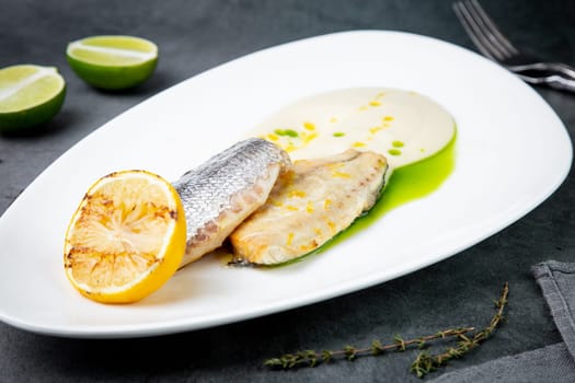 pieces of fried fish with sauce and fried lemon on a white plate