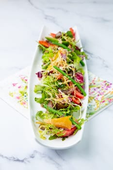 green salad with cherry tomatoes on a white oblong plate