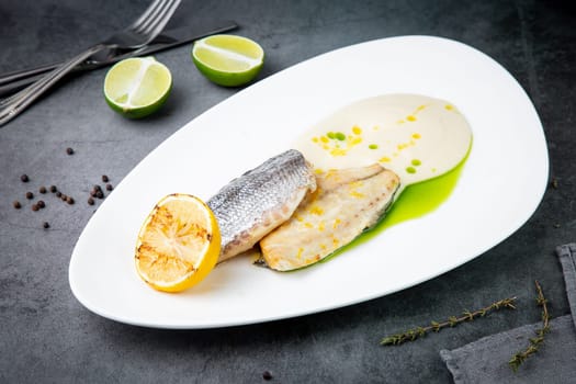 pieces of fried fish with sauce and fried lemon on a white plate