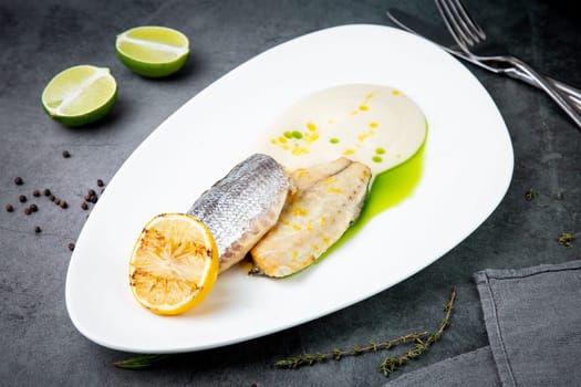 pieces of fried fish with sauce and fried lemon on a white plate