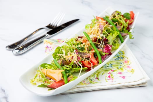 green salad with cherry tomatoes on a white oblong plate