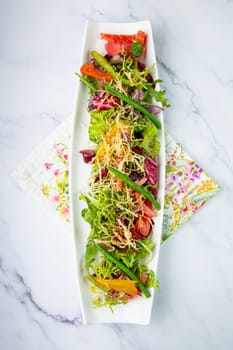 green salad with cherry tomatoes on a white oblong plate