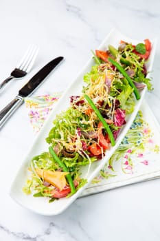 green salad with cherry tomatoes on a white oblong plate