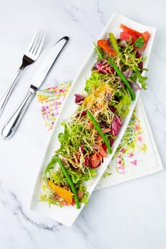 green salad with cherry tomatoes on a white oblong plate