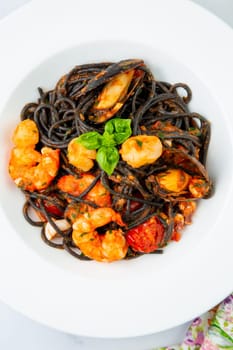 black noodles with mussels, shrimp, tomatoes and herbs