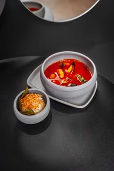 Tom Yum Kung spicy Thai soup with shrimp in a grey bowl on a dark stone background, top view, copy space. High quality photo