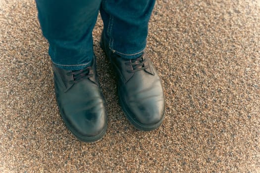 a girl walks on an autumn deserted beach. women's feet in brown leather boots on the sand of an autumn beach.