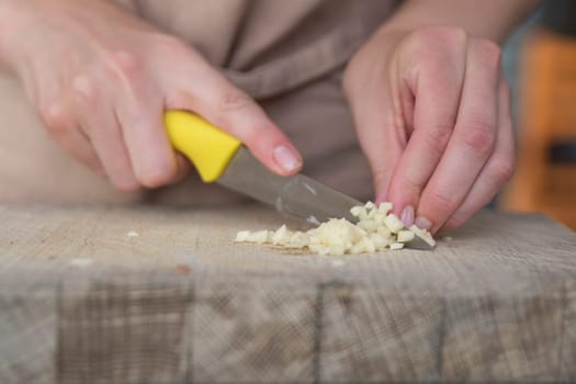 A woman cuts garlic with a knife close-up. Cutting garlic for salad or as an aromatic spice for meat. High quality photo