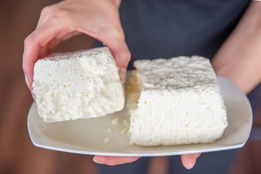 Hand holds cottage cheese close-up. Place cottage cheese on the table. Healthy eating concept. High quality photo