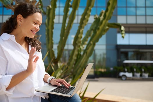 Smiling young adult woman using laptop, talks with business partners via video link, negotiating, sharing business project and new startup. People. Online communication. Career and recruitment concept