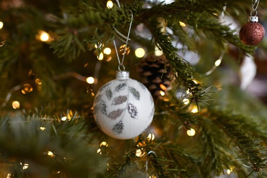 White ball and toys hanging on a Christmas tree